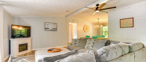 A living room with a sectional sofa, a flat-screen TV, a fireplace, and a ceiling fan.