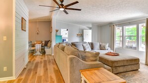 A spacious living room with a large sofa, a wooden coffee table, and a ceiling fan. - Private Dock: Pet-friendly Home on Lake Sinclair (Milledgeville)