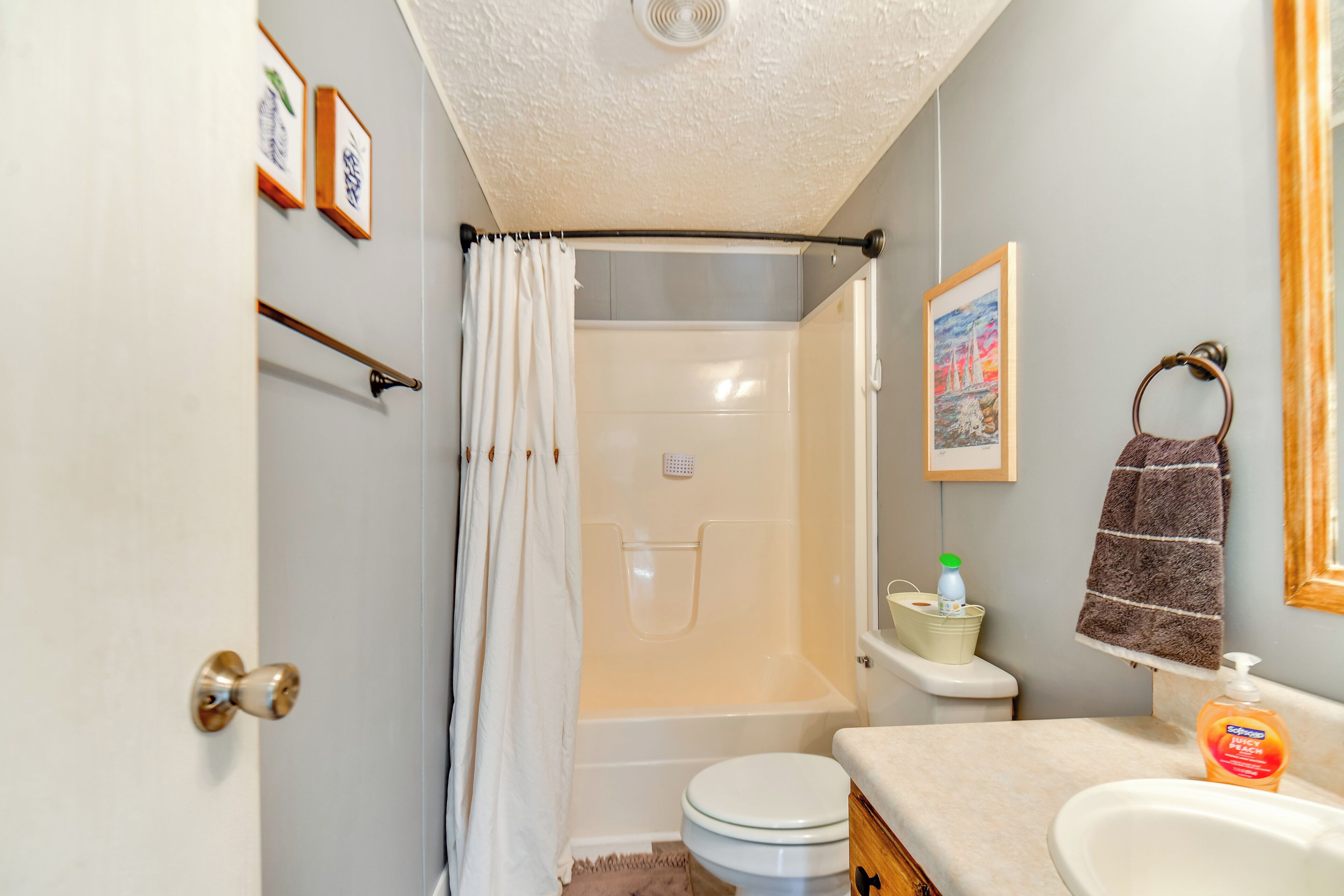 A bathroom with a shower, toilet, sink, and a towel hanging on the wall.