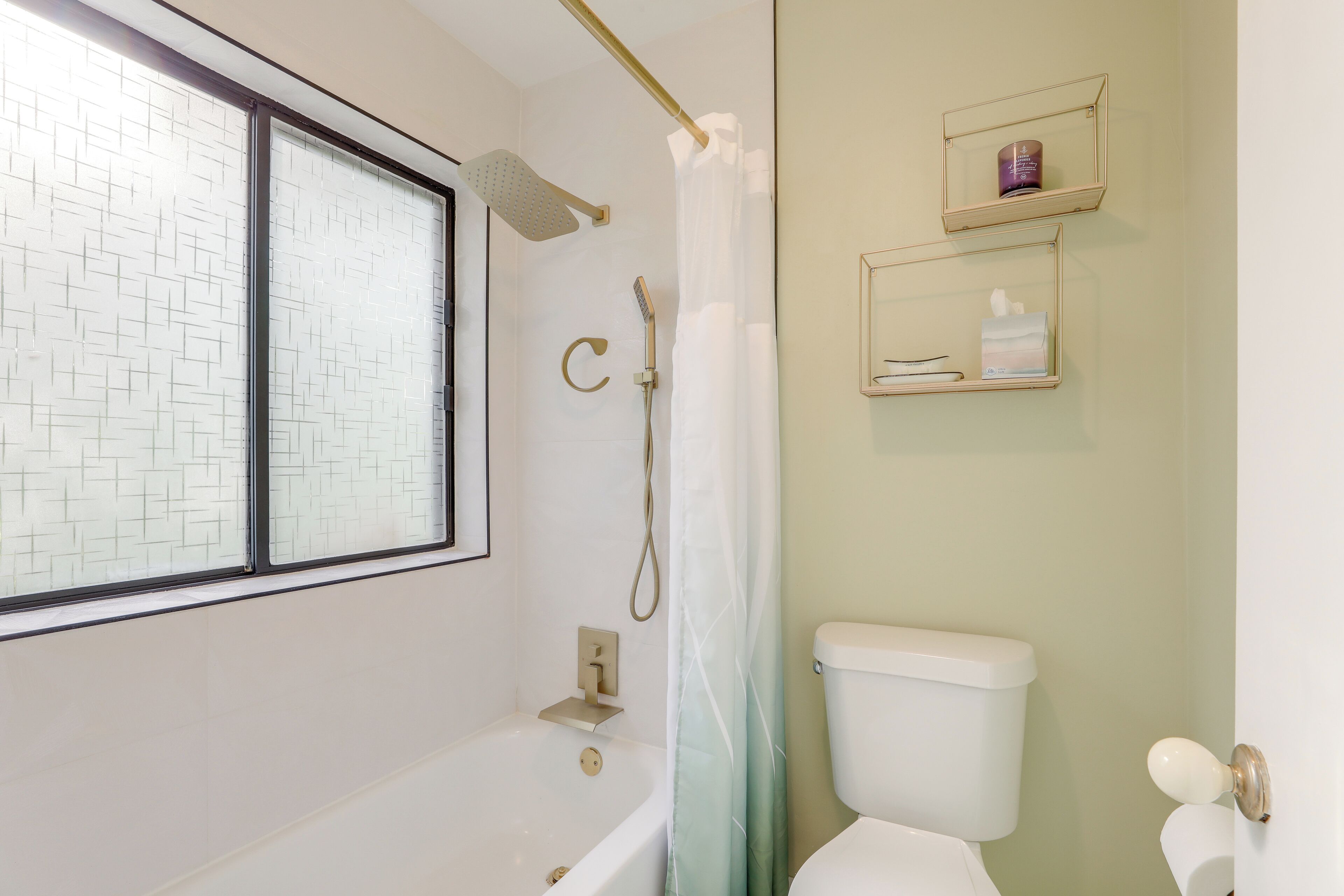 Une salle de bain avec une baignoire, une douche, des toilettes et une fenêtre.