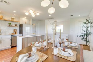 Una cocina moderna con armarios blancos, horno empotrado y un comedor para seis personas con una mesa de madera y seis sillas.