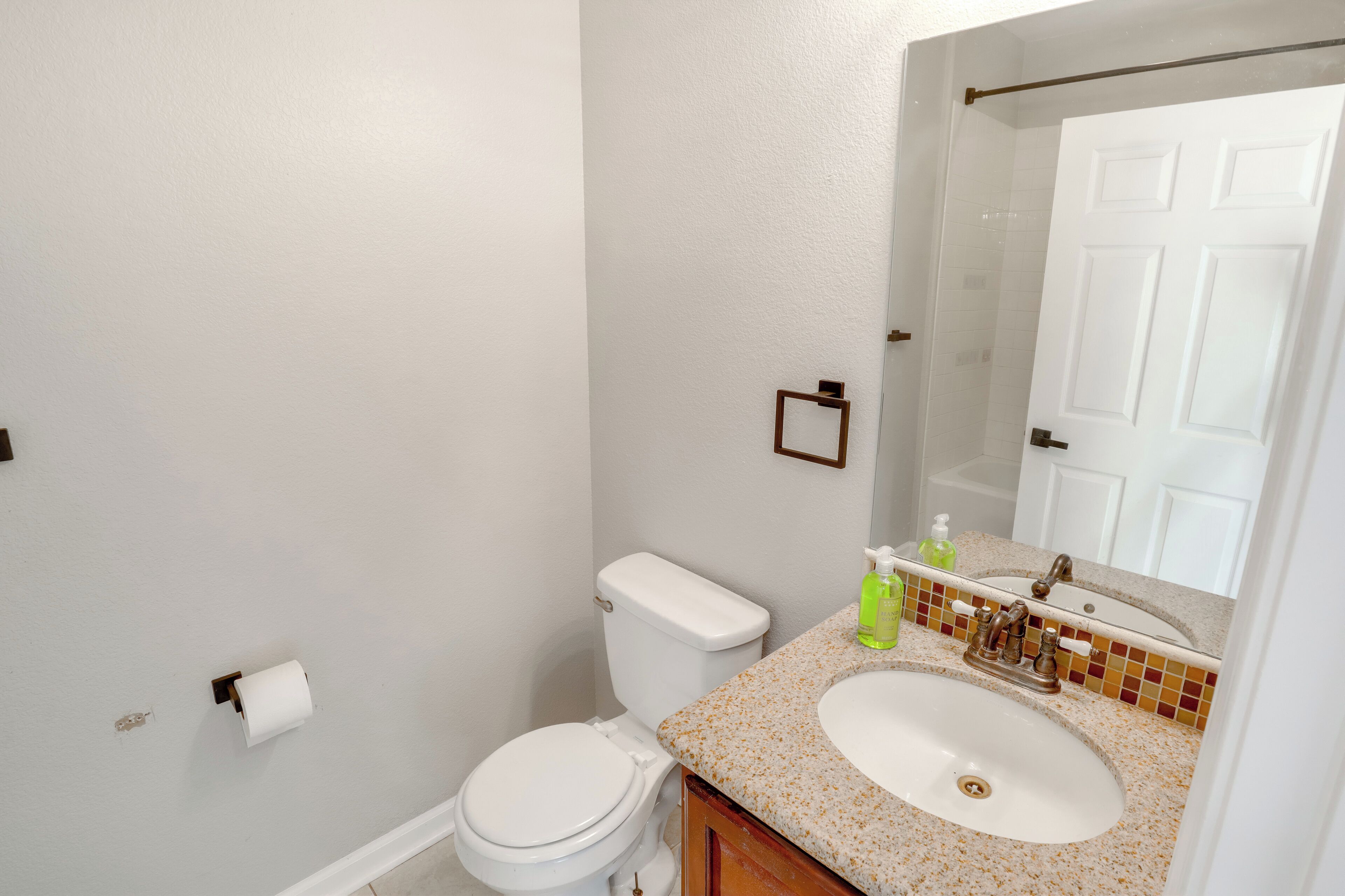 A bathroom with a toilet, sink, and mirror.