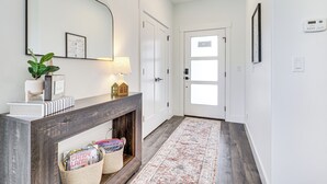 A hallway with a dark wooden console table, a mirror, a lamp, a fireplace, and a patterned rug. - 6 Mi to Great Salt Lake: Mtn-view Retreat! (Tooele)