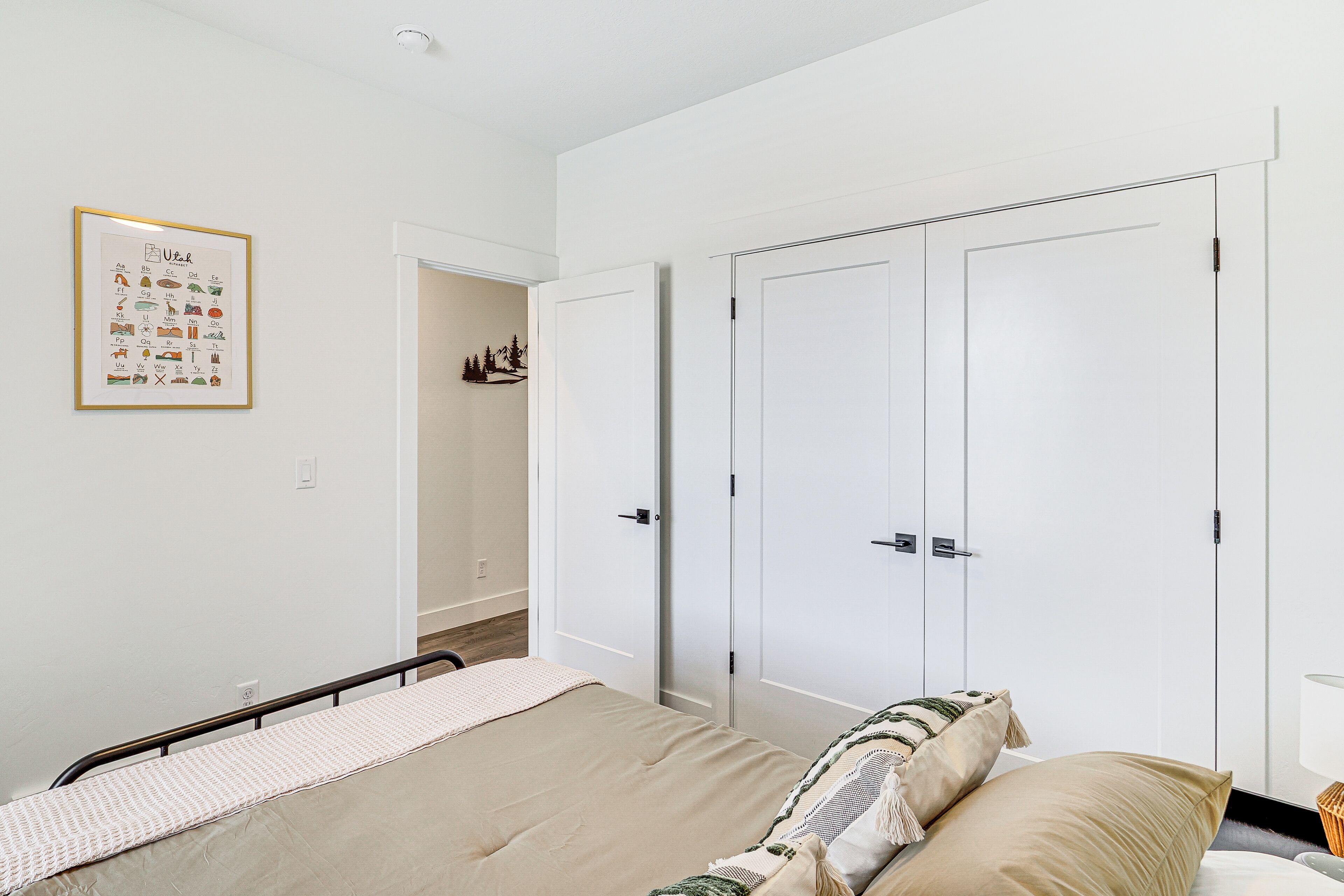 A bedroom with a bed, a bedside table, a nightstand, a wardrobe, and a framed picture on the wall.