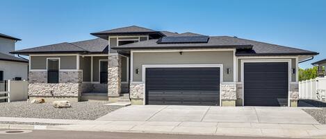 A modern two-story house with a garage, stone accents, and solar panels.