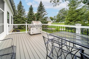 Une terrasse avec un barbecue, du mobilier d’extérieur et une vue sur les arbres et les maisons.