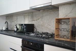 Une cuisine équipée d’une cuisinière à gaz, d’un four à micro-ondes et d’un meuble à vin.
