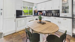 Une cuisine moderne avec des meubles blancs, une table ronde en bois et deux chaises.