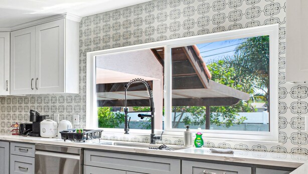 A kitchen with a large window, white cabinets, and a stainless steel sink. - Sunny Spanish Villa Pool Parking Privacy (Hacienda Heights)