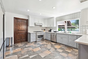 A modern kitchen with grey cabinets, a stainless steel oven, and a patterned backsplash. - Sunny Spanish Villa Pool Parking Privacy (Hacienda Heights)