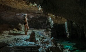 A cave interior with a person standing near a rock formation. - Premium Condo With Terrace Pool View (Tulum)
