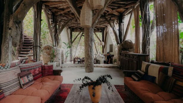 A rustic interior with wooden beams, a central wooden table, and a sofa with patterned cushions. - Luxury Penthouse w Private Pool Stunning Views (Tulum)