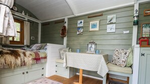 Un interno accogliente di una baita, con un letto, un tavolo con una lanterna e diverse decorazioni alle pareti.
