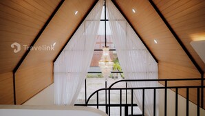 Een kamer met een driehoekige vorm, houten wanden en een groot raam aan de voorzijde.