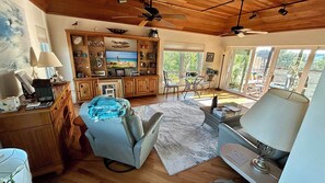 Relax in this cozy living area with a plush sofa, chair, and coffee table, featuring a mounted television and ceiling fans.