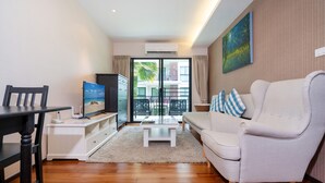 A modern living room with a sofa, TV, and a dining area with a table and chairs. - Title Rawai Tropical View Apartment B209 (Rawai)