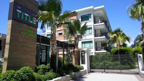 A modern hotel with a sign reading "The Title Phase III West Wing". - Title Rawai Tropical View Apartment B209 (Rawai)