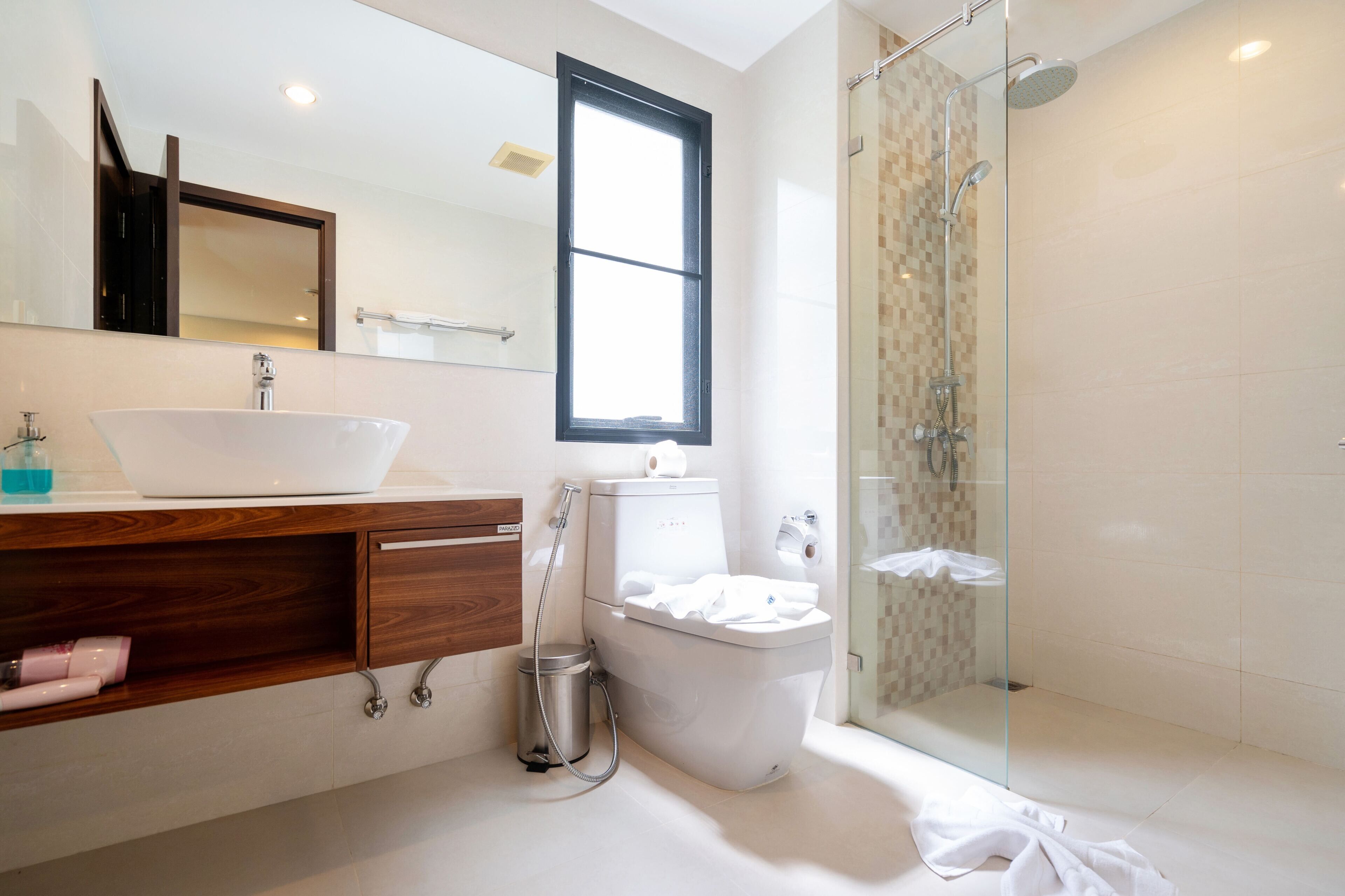 A modern bathroom with a large sink, toilet, and glass-enclosed shower.