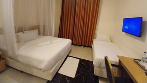 A hotel room with a bed, a smaller bed, a desk, a chair, a TV, and curtains. - Hotel Discretion LTD (Migori)