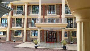 A multi-story hotel with balconies, a central entrance, and potted plants. - Hotel Discretion LTD (Migori)