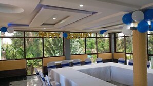 A banquet hall with a 'Happy Birthday' banner, large windows, and tables set for an event. - Hotel Discretion LTD (Migori)