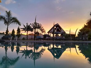 A pool reflecting palm trees and a gazebo at sunset. - Hotel Discretion LTD (Migori)