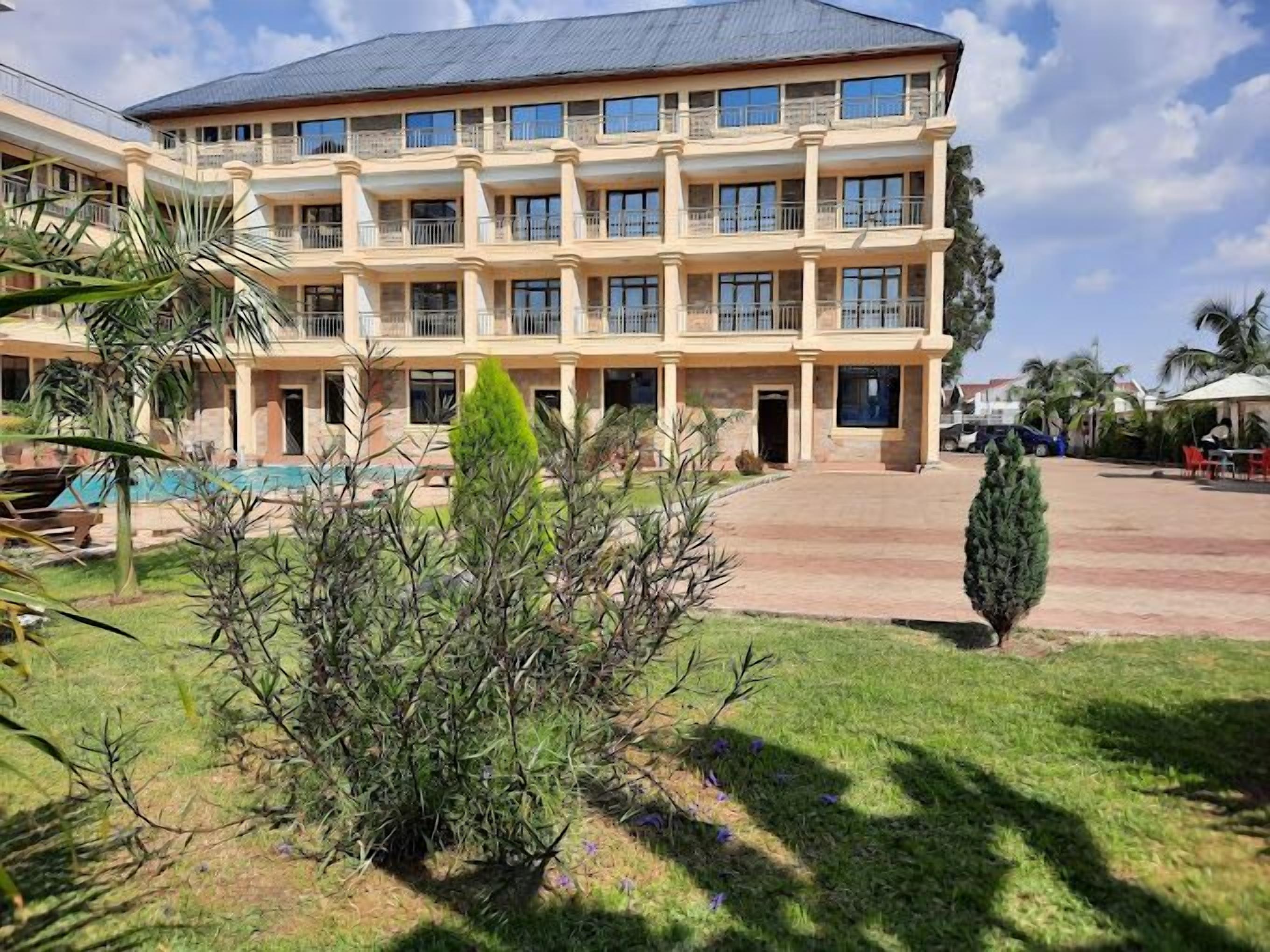 A multi-story hotel with a central courtyard, balconies, and a swimming pool.