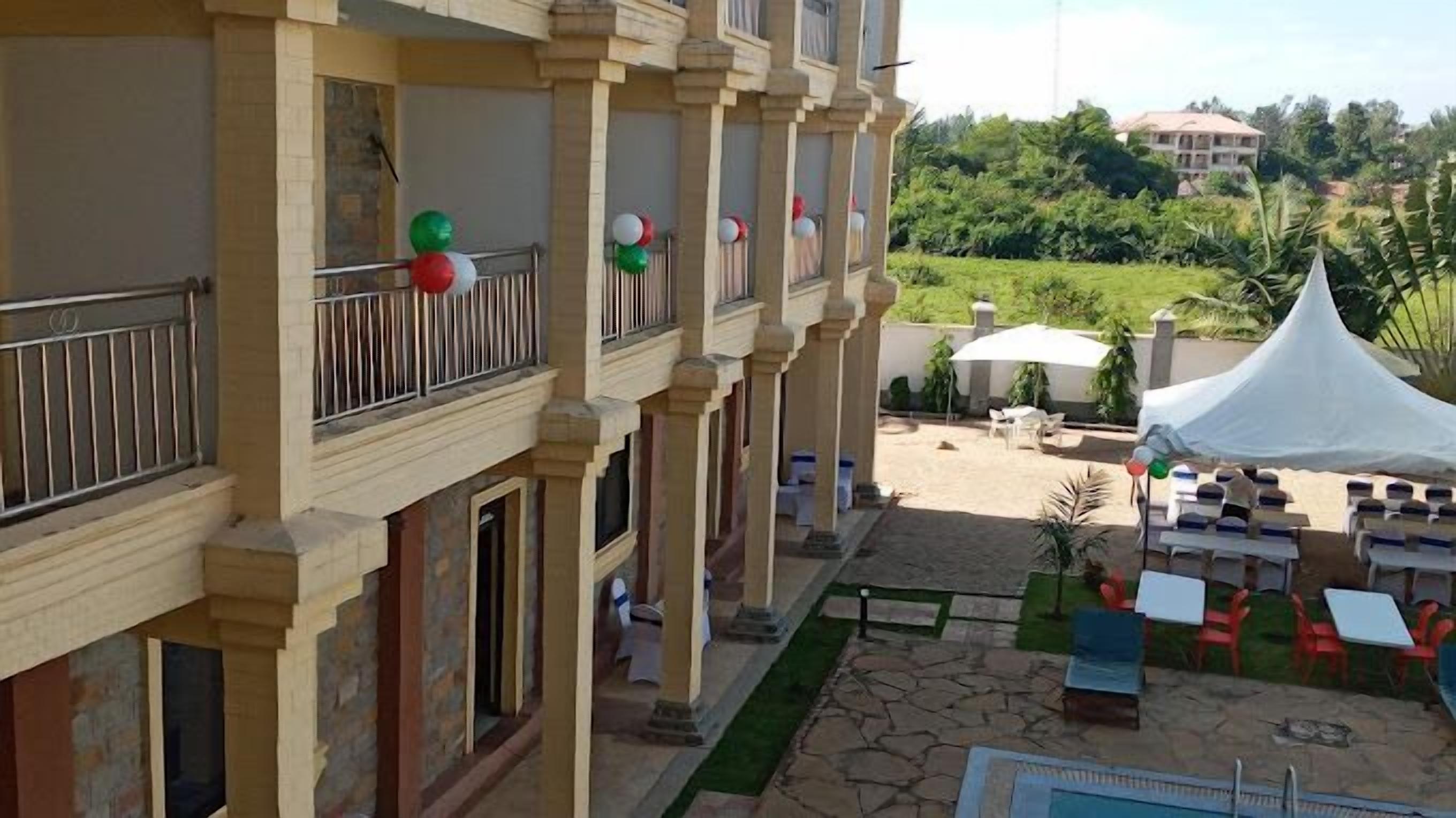 A hotel with a covered outdoor area, multiple balconies, and a pool.