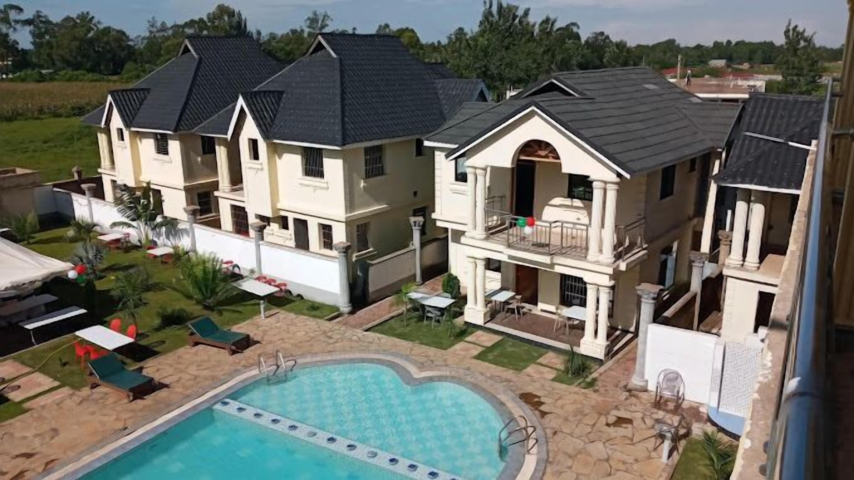 Un'ampia casa con piscina, diversi balconi e un giardino curato.