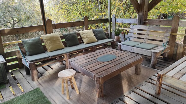 A wooden deck with a sofa, a bench, and a table.