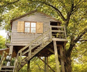A wooden treehouse with a staircase, a window, and a door.