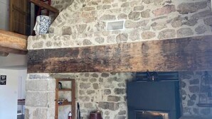 A stone fireplace with a wooden mantel, a bench, and a rustic interior.
