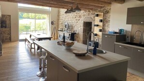 A kitchen with a large island, stone walls, and a rustic ceiling.