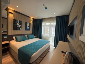 Een moderne hotelkamer met een groot bed, een bureau, een televisie en uitzicht op buiten.
