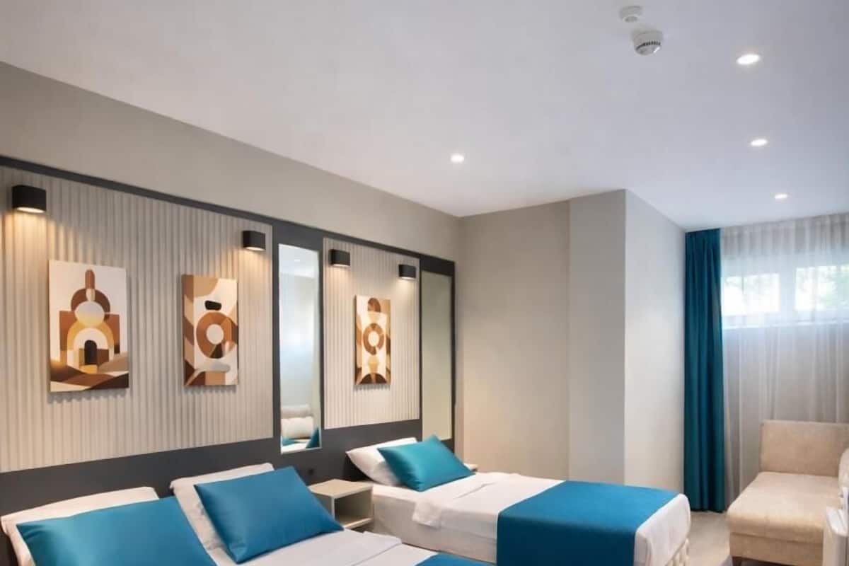 A hotel room with two beds, a sofa, and a chair.