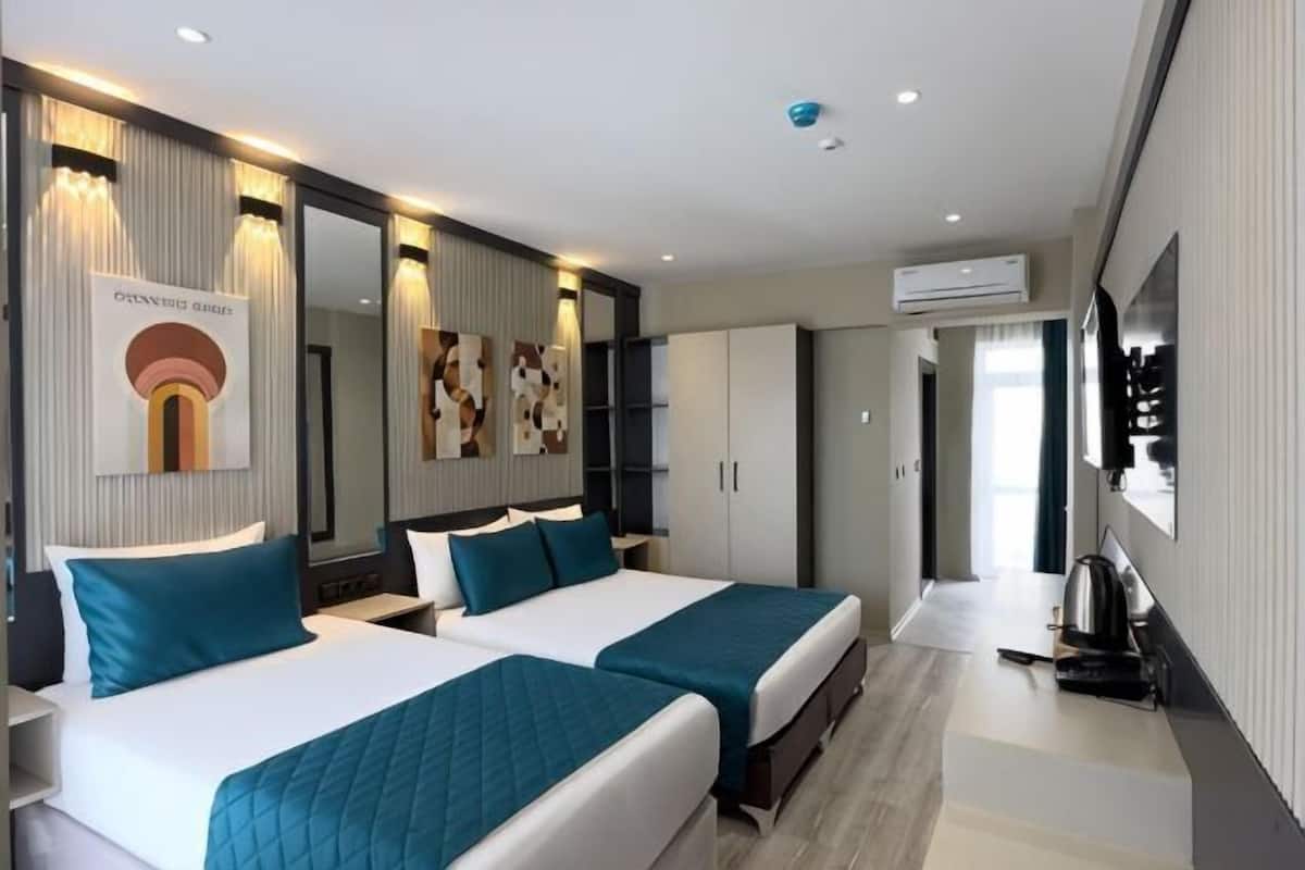 A hotel room with two beds, a large mirror, a wardrobe, and an air conditioning unit.