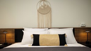 A neatly made bed with white and black pillows, a woven throw blanket, and a macrame wall hanging. - Nobia 5 (Athens)