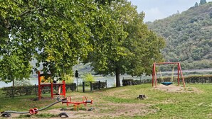 Ein Spielplatz mit Schaukeln und Sportgeräten in der Nähe eines Gewässers.