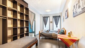 Ein Schlafzimmer mit einem Bett, einem Nachttisch, einem Sessel, einem Kleiderschrank und einem Fenster mit Vorhängen.