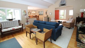 A living room with a blue sofa, wicker chairs, a chess table, and a wooden bench.