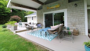 A covered patio with outdoor furniture, a large fish mural, and a sliding glass door.