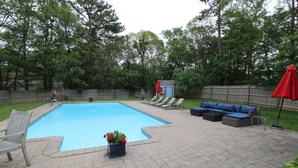 A backyard with a swimming pool, patio furniture, and a small shed.