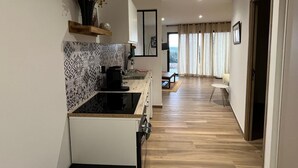 A modern kitchen with a patterned backsplash, a coffee maker, and a wooden shelf with dried flowers. - Large 50m2 studio, in the heart of the Maquis, San gavino di Figari (San gavinu Di figari)