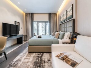 Una camera d'hotel moderna con un letto grande, una televisione a schermo piatto, una scrivania e un divano.