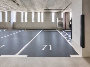 Un parcheggio multipiano con posti auto delimitati e un estintore a vista.