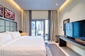 A hotel room with a large bed, a television, and a view of the cityscape.