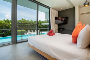 Een moderne hotelkamer met een groot bed, een televisie en uitzicht op een zwembad.