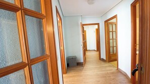 A hallway with wooden doors and a trash bin. - EUROMAR - 3 bedroom apartm - Cullera - wifi (Cullera)