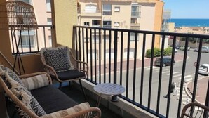 A balcony with wicker furniture, a small round table, and a view of a street and buildings. - 3 bedroom apartment in val d'arcomie (Val d'Arcomie)