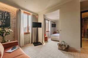 A hotel room with a sofa, a TV, a bed, and a handbag on the floor. - Rimon Place-Kosher (Venice)